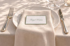 Printable sage green border wedding name card resting on a cream napkin draped over a white dinner plate, with elegant script lettering for a romantic country club wedding table setting.