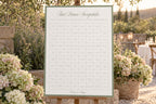 A1 First Dance Sweepstake wedding sign with a sage green border, displayed on an easel among white flowers at an outdoor garden wedding reception.