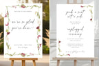 Matching botanical wedding signs displayed on easels, featuring romantic script lettering and burgundy floral accents.