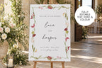 Burgundy botanical wedding welcome sign displayed on a wooden easel at a garden ceremony, featuring personalised couple names, romantic script lettering and a floral border with editable text, fonts and colours.