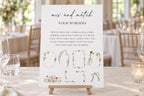 Mix and match floral wedding sign borders displayed on a tabletop easel, featuring botanical frames, illustrated bows and pink flowers for creating personalised wedding signage.