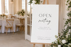 Editable open seating wedding sign template displayed on easel at wedding reception entrance, minimalist black and white wedding seating sign, modern open seating chart alternative, elegant wedding welcome signage, printable A1 wedding reception sign, instant download Canva template.