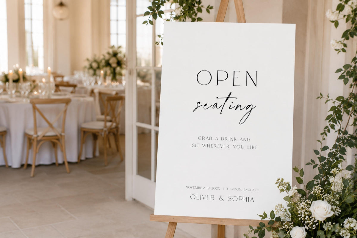Editable open seating wedding sign template displayed on easel at wedding reception entrance, minimalist black and white wedding seating sign, modern open seating chart alternative, elegant wedding welcome signage, printable A1 wedding reception sign, instant download Canva template.