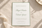 Elegant white wedding invitation with sage green border and romantic script names, displayed on ivory linen in natural sunlight. Classic minimalist wedding stationery for an old money wedding theme.