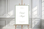 Classic wedding welcome sign with sage green script and a slim border, displayed on a wooden easel in a white panelled room. Elegant personalised wedding entrance signage styled for a timeless manor house celebration.