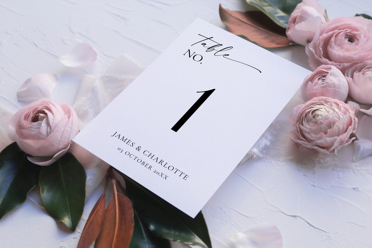 Flat lay of printable wedding table number template with romantic flowers – editable black and white reception table sign for elegant wedding décor.