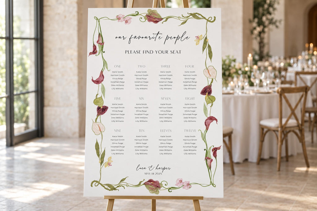 Botanical wedding seating chart template on a wooden easel at an elegant reception, featuring guest names grouped by table within a burgundy calla lily and green foliage border.