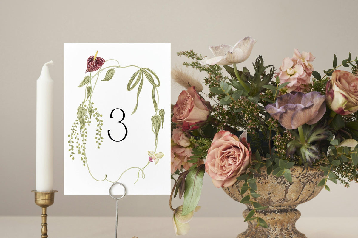 Floral wedding table number three with delicate green vines and burgundy flowers, styled beside a romantic garden-inspired centrepiece.