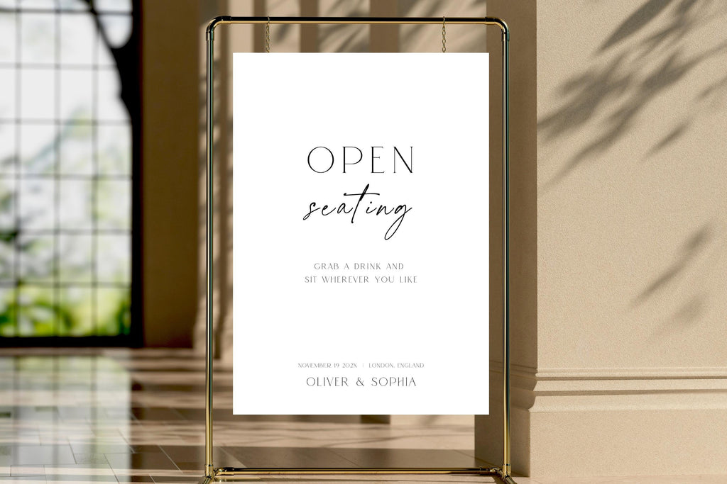 Framed open seating wedding sign template displayed in luxury wedding venue, editable wedding reception signage, modern minimalist wedding decor printable, black and white open seating sign, elegant wedding entrance display, instant download Canva template.