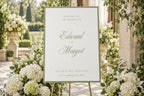Elegant sage green wedding welcome sign surrounded by white hydrangeas and garden greenery. Romantic script lettering and a simple border create an old money garden wedding entrance with timeless country club styling.