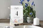 Rustic garden style wildflower wedding table number printable, editable Canva template shown on dinner table with flowers, perfect for boho wedding reception decor.