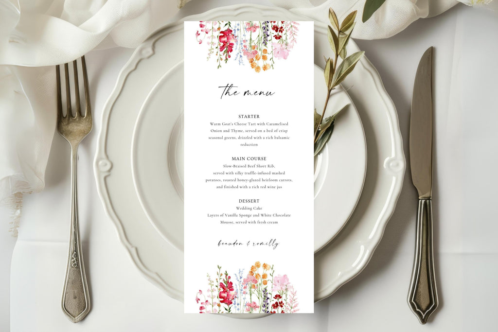 Floral wedding menu card displayed on a white plate at an elegant reception table, featuring a colourful pink and coral flower design with matching wedding stationery.