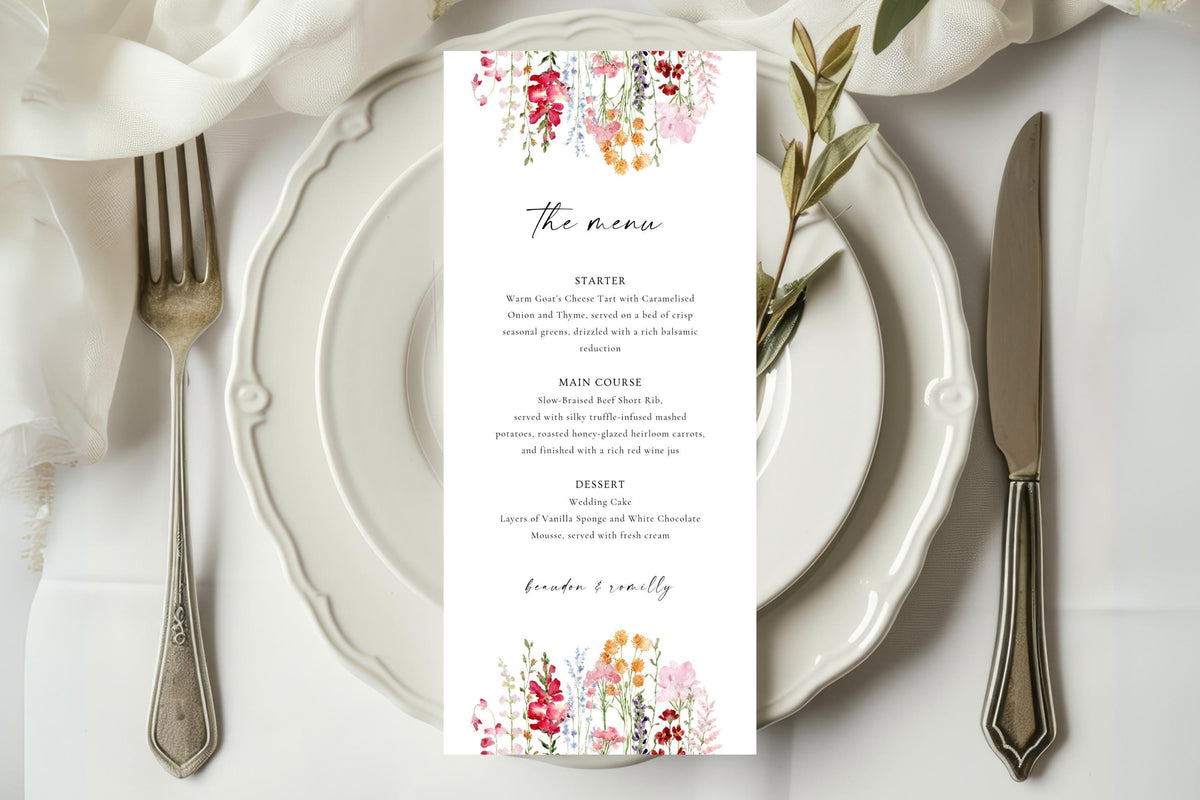 Floral wedding menu card displayed on a white plate at an elegant reception table, featuring a colourful pink and coral flower design with matching wedding stationery.