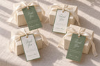 Sage green and ivory wedding favour tags on four cream gift boxes with satin bows, featuring romantic script lettering in two coordinating designs for an elegant old money wedding.
