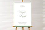 Minimalist sage green wedding welcome sign on a wooden easel against a neutral background. White portrait design with a delicate green border and elegant script names, ideal for classic romantic wedding entrance signage.