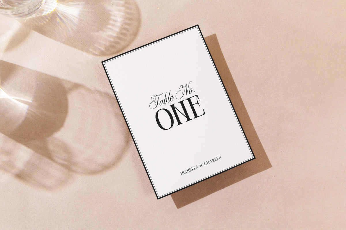 Minimalist printable wedding table number design in soft golden light mockup, editable black and white table number template for elegant reception tables, modern DIY wedding signage.