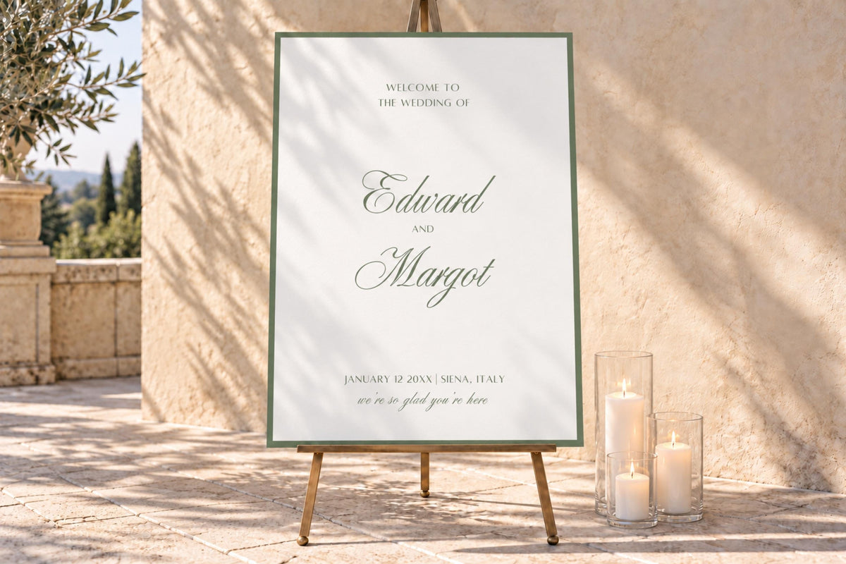 Personalised sage green wedding welcome sign with elegant script names and a fine border, displayed on a wooden easel beside glass candle holders in a sunlit stone courtyard.