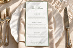 Elegant printable wedding dinner menu with sage green lettering and a classic border, resting on a folded ivory napkin and scalloped plate in natural sunlight, ideal for romantic country club wedding table styling.