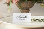 Minimalist wedding place card on ivory plate with greenery, editable name card template, classic script font place setting for elegant wedding reception.