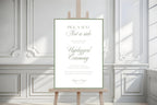 Minimalist sage green wedding seating sign on a wooden easel against white panelled walls, with refined typography and “Pick a seat, not a side” wording.
