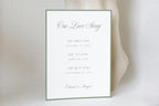 Our Love Story wedding timeline sign with sage green lettering and a slim border, featuring relationship milestones on a white card against a softly draped neutral background.
