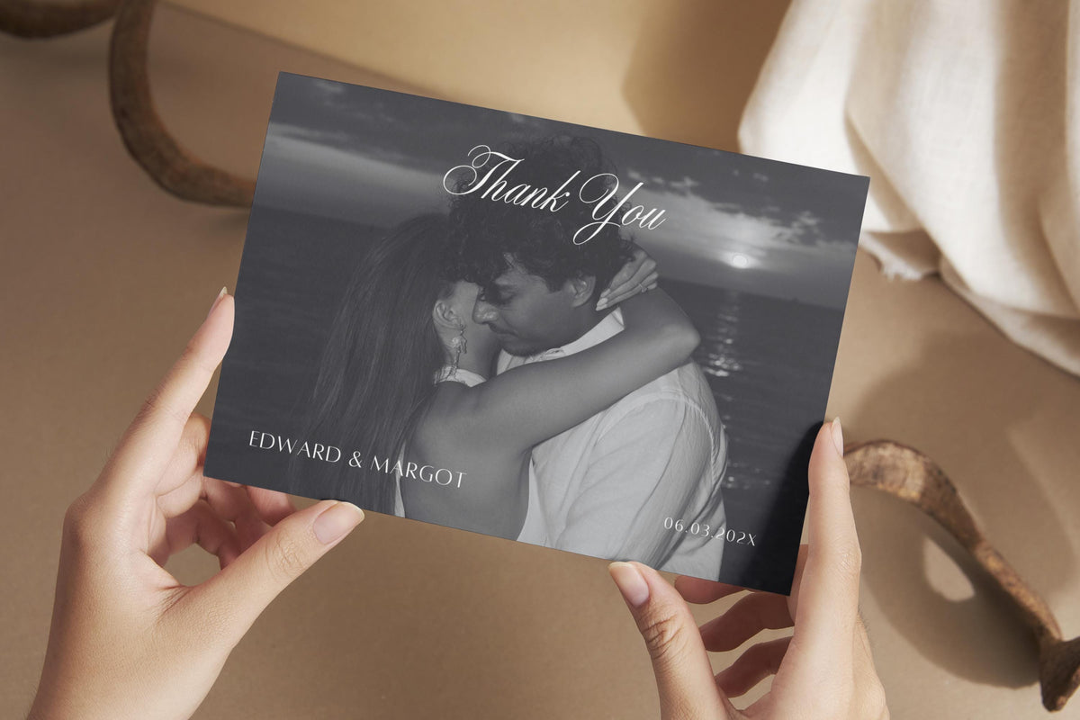 Black and white photo wedding thank you card held in hands, featuring a newlywed portrait, delicate script lettering and personalised names for a romantic editorial wedding thank you postcard.