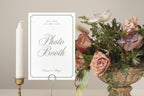 Editable wedding photo booth sign in a simple white and sage green design, styled with candles and a colourful flower arrangement for a wedding reception.