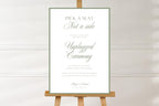 Simple sage green open seating wedding sign on a wooden easel against a soft white background, showing the full design and elegant ceremony wording.