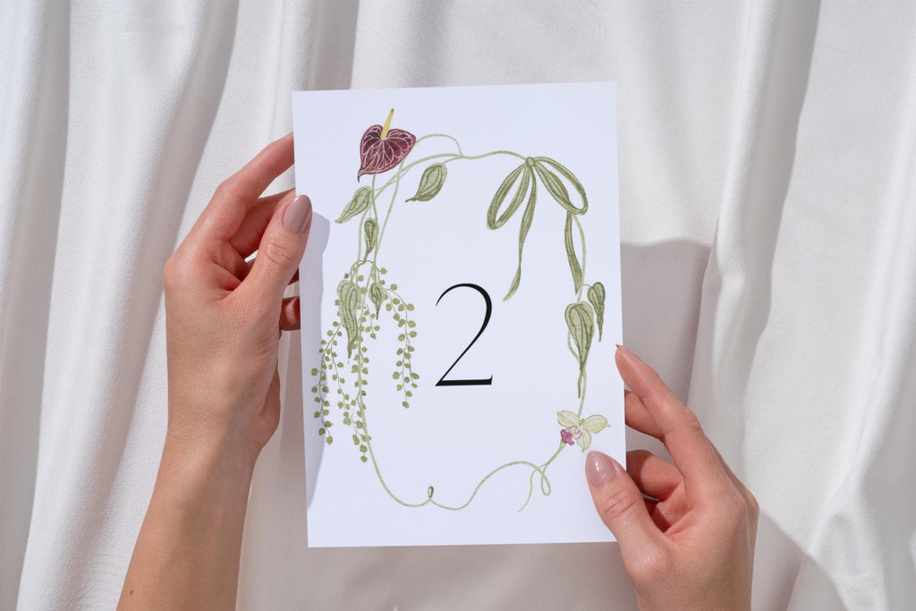 Bride holding an editable floral wedding table number two, featuring whimsical wildflowers and a delicate botanical border.