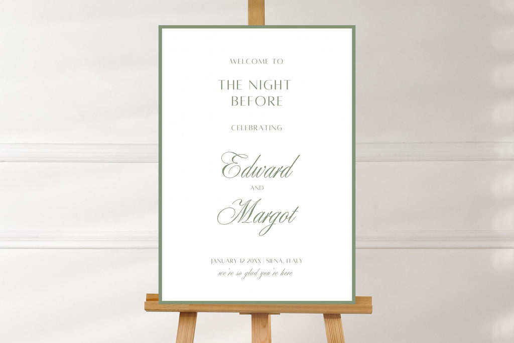 White and sage green “The Night Before” rehearsal dinner sign featuring a thin green border, classic serif lettering and script names. Minimalist wedding welcome sign displayed on a wooden easel against a neutral wall.