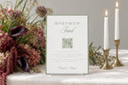 Sage green honeymoon fund wedding sign with a QR code, displayed on a reception table with candles and floral arrangements; editable honeymoon fund sign for wedding guests.