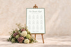 Old money wedding seating chart with sage green border and elegant script, displayed on a wooden easel beside pastel flowers against a textured stone wall. Printable wedding table plan with an Our Favourite People heading.
