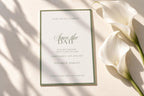 Elegant sage green save the date card beside white calla lilies with soft sunlight and shadows. Printable wedding announcement template with romantic script typography and a minimalist green border.