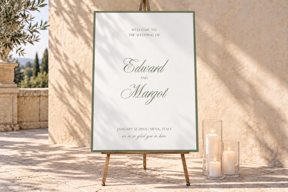 Sage green wedding welcome sign with romantic script names and a fine green border, displayed on an easel beside ivory candles in a sunlit courtyard. Elegant old money wedding entrance signage with soft natural shadows.
