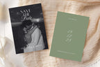 Sage green and black and white photo save the date cards on textured ivory fabric, featuring a romantic couple portrait and stacked script date for classic wedding stationery.