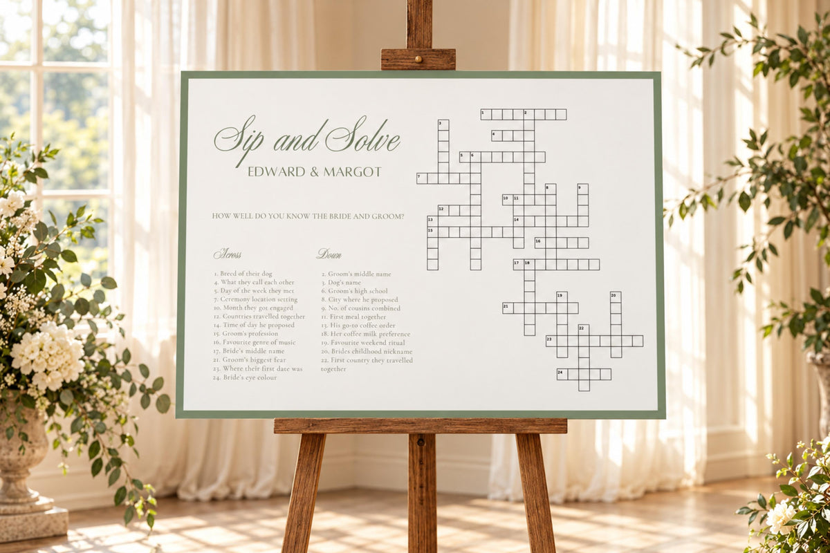 Sage green Sip and Solve wedding crossword sign displayed on a wooden easel in a bright wedding reception setting with soft white draping and greenery.