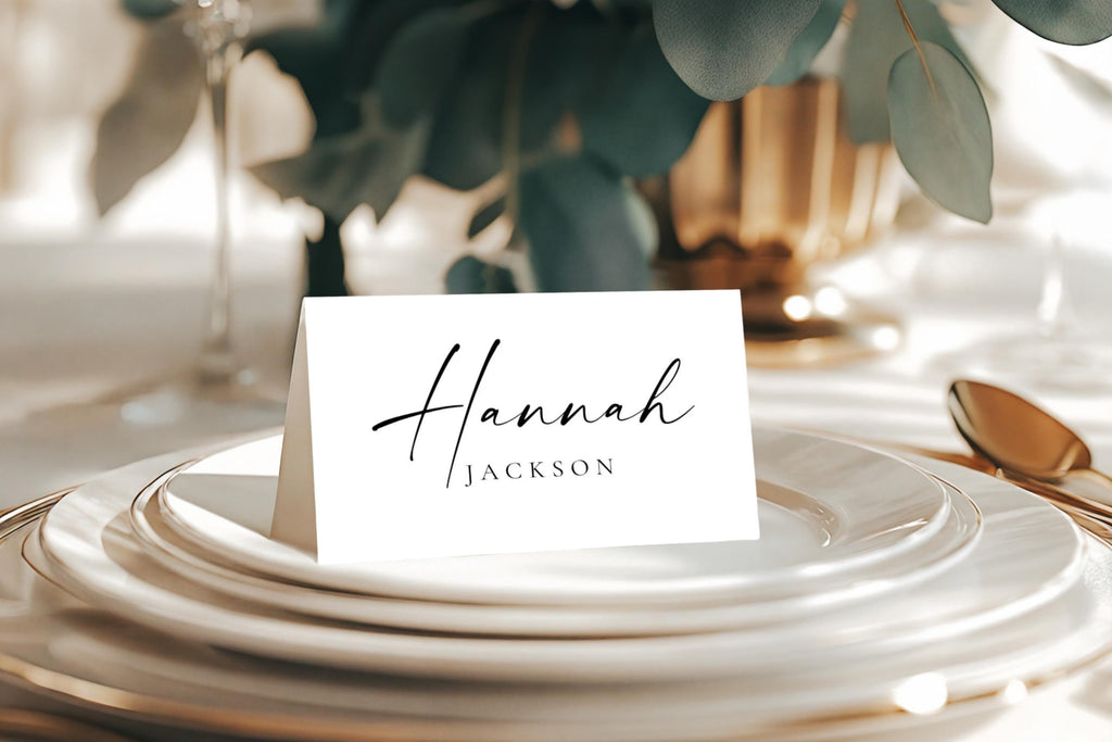 Minimalist folded wedding place card with script and serif font on modern neutral tablescape, editable Canva template