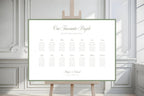Minimalist landscape wedding seating chart template with a sage green border displayed on an easel in front of elegant white panelled doors.