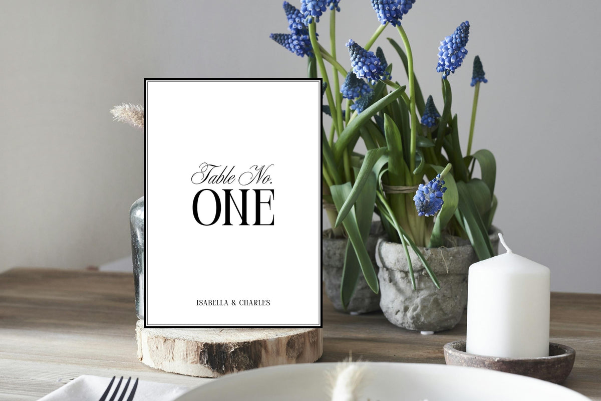 Wedding table number printable in black and white displayed in rustic wood slice setting, editable Canva table number sign for modern minimalist wedding décor and reception styling.