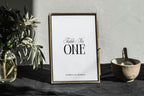 Minimalist wedding table number template displayed in a gold frame on styled table, editable black and white table number design for modern wedding décor, printable Canva wedding signage.