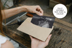 Personalised photo wedding thank you card being placed into a cream envelope above a rustic wooden table, with an elegant black and white portrait and editable text, fonts and colours.