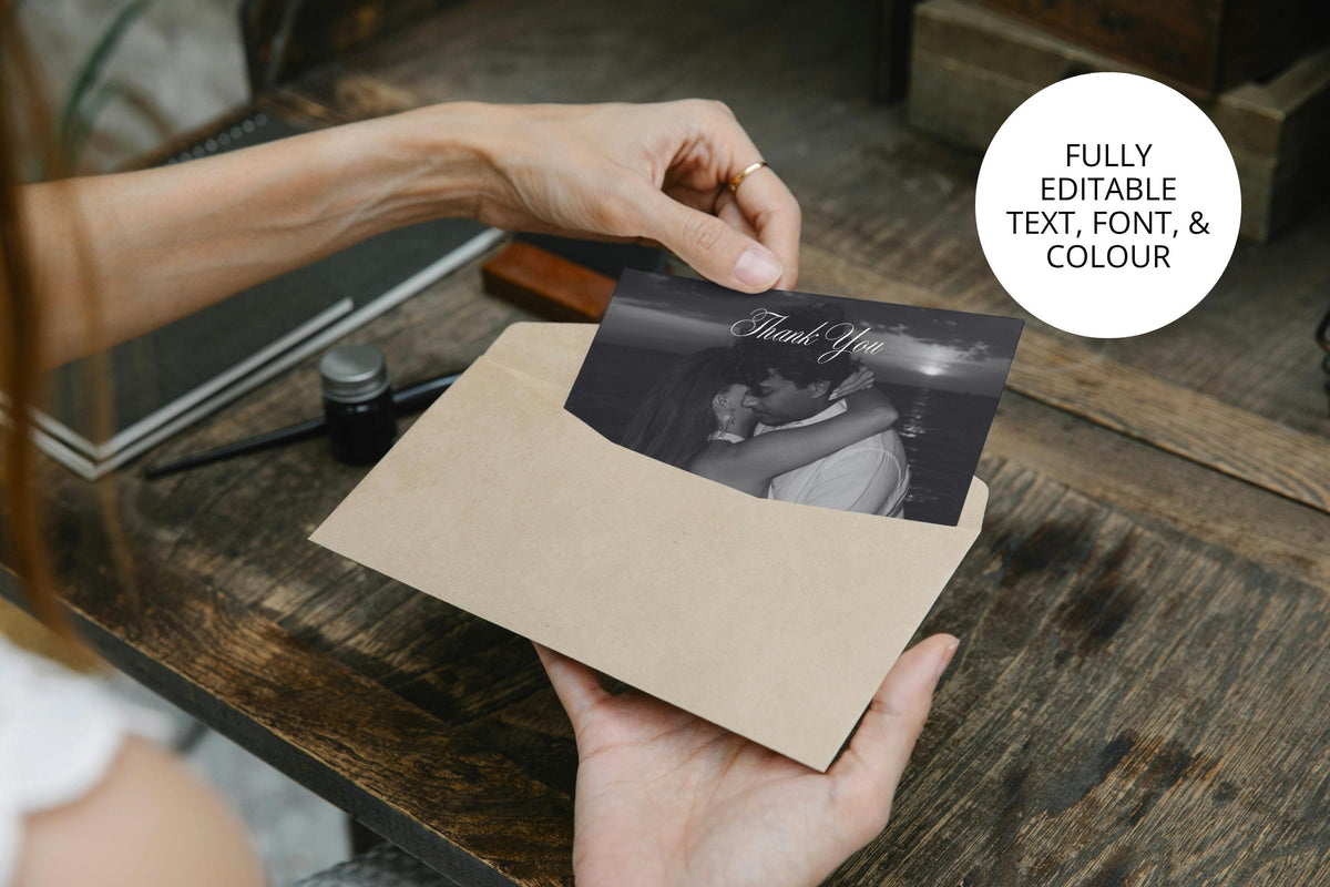 Personalised photo wedding thank you card being placed into a cream envelope above a rustic wooden table, with an elegant black and white portrait and editable text, fonts and colours.