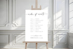 Elegant black and white wedding order of the day sign, minimalist order of events poster, printable wedding timeline template displayed indoors