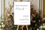 “We’re Married, Let’s Party” wedding sign displayed on easel with florals, minimalist wedding reception sign Canva template for modern weddings