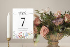 Editable wildflower wedding table number template displayed on reception table with candle and floral centerpiece, printable boho wedding table decor card.