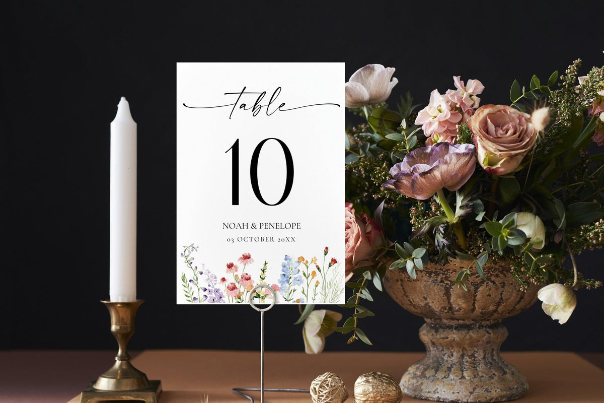 Printable wildflower wedding table numbers sign, editable Canva template displayed with candle and floral centerpiece for rustic boho reception.